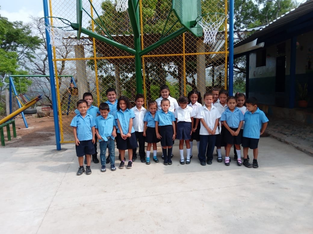 A class of students in uniform in front of the new play structures